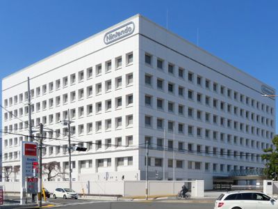 Headquarters of Nintendo which is a white building that resembles a cube with windows on a blue sky background view from the corner of a street